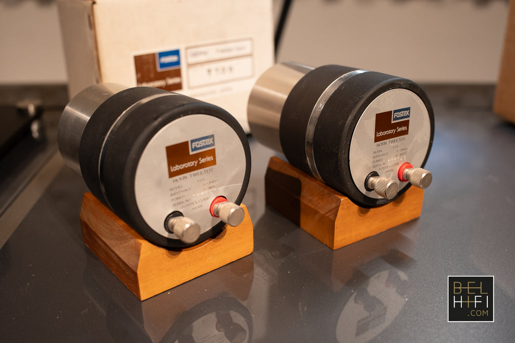 Two audio equipment components on wooden stands with a blurred background